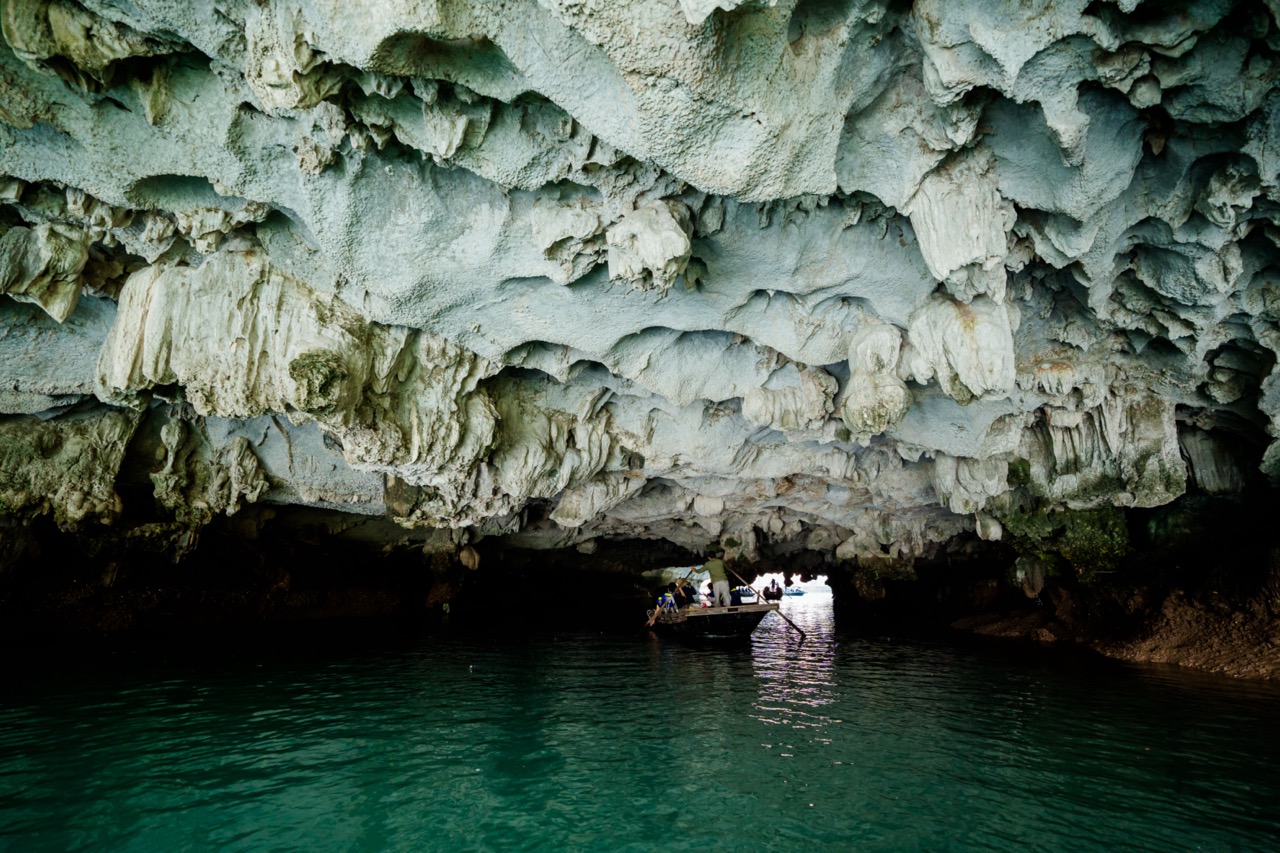 Cave interior in Halong Bay with boat passing underneath, scenic and adventurous atmosphere.