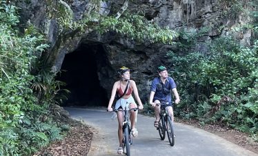 Two travelers cycling through lush forest trail in Sapa, Vietnam, enjoying trekking adventure in sce.