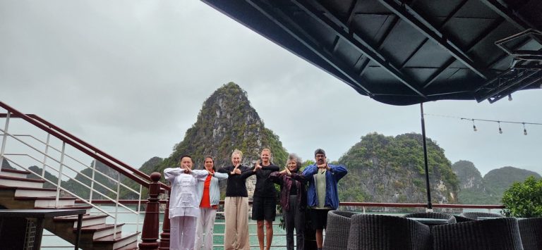 Scenic view of Halong Bay from a cruise balcony with a group of travelers enjoying the landscape.