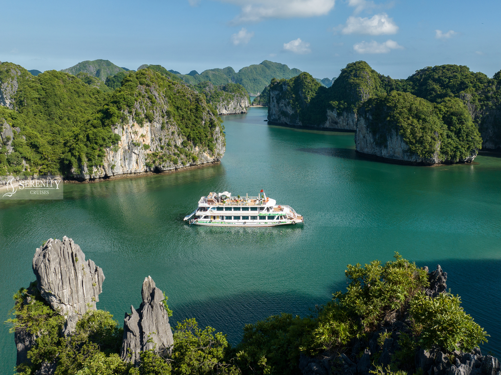 A cruise boat sailing through the stunning limestone karsts and emerald waters of Halong Bay, Vietna.