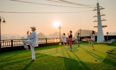 Sunset yoga on cruise deck with people practicing yoga and meditation in Halong Bay at sunset, peace.