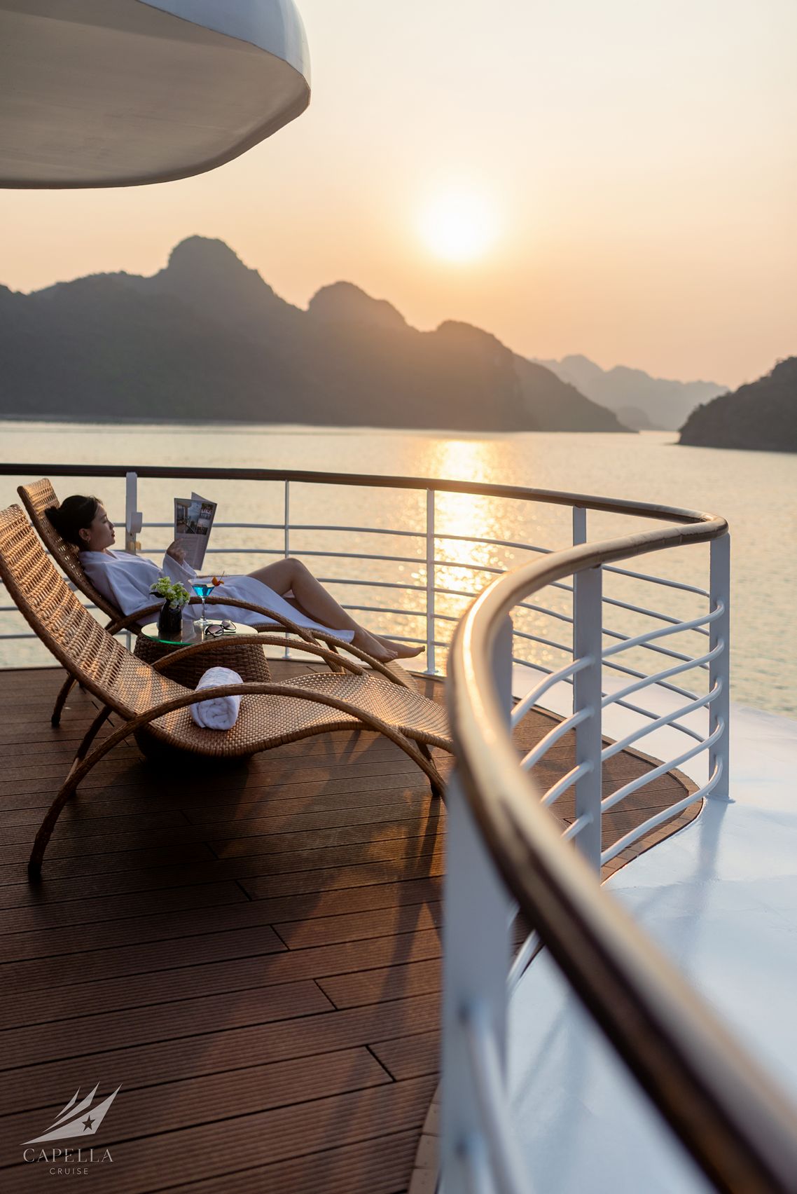 Relaxing cruise ship deck with scenic mountain and sunset views, perfect for luxury Vietnam travel.
