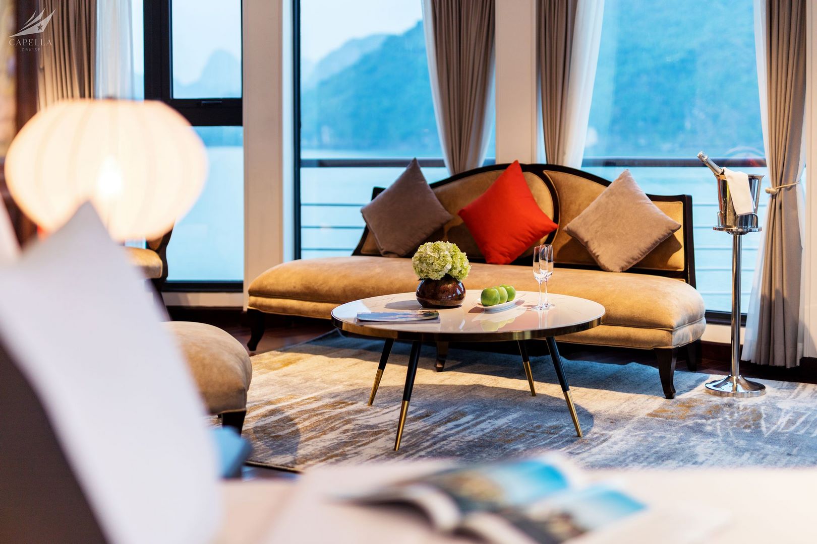 Luxurious hotel living room with elegant sofa, cushions, decor, and scenic water views, perfect for relaxing vacations.