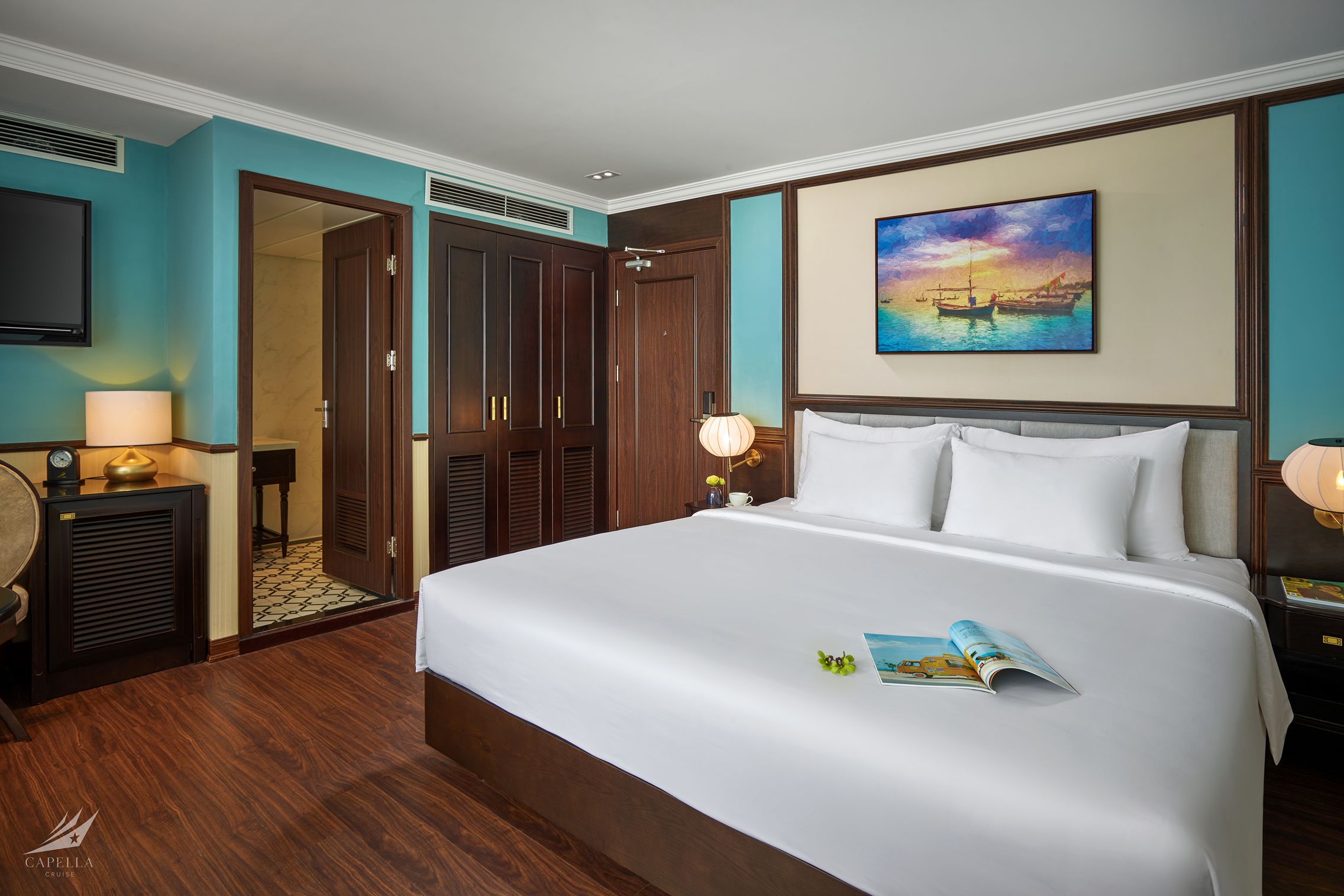 Bright hotel room with spacious bed, modern decor, and ocean view artwork for a relaxing stay.