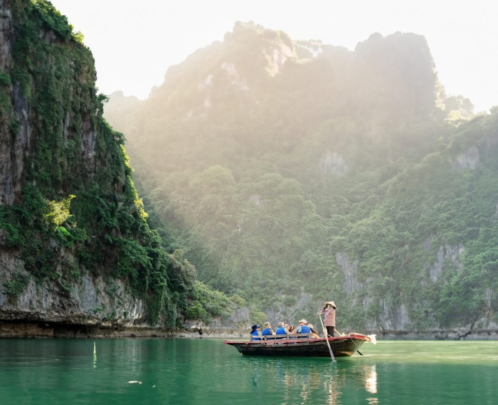 Tranquil boat tour through lush green limestone karsts in Halong Bay, Vietnam.