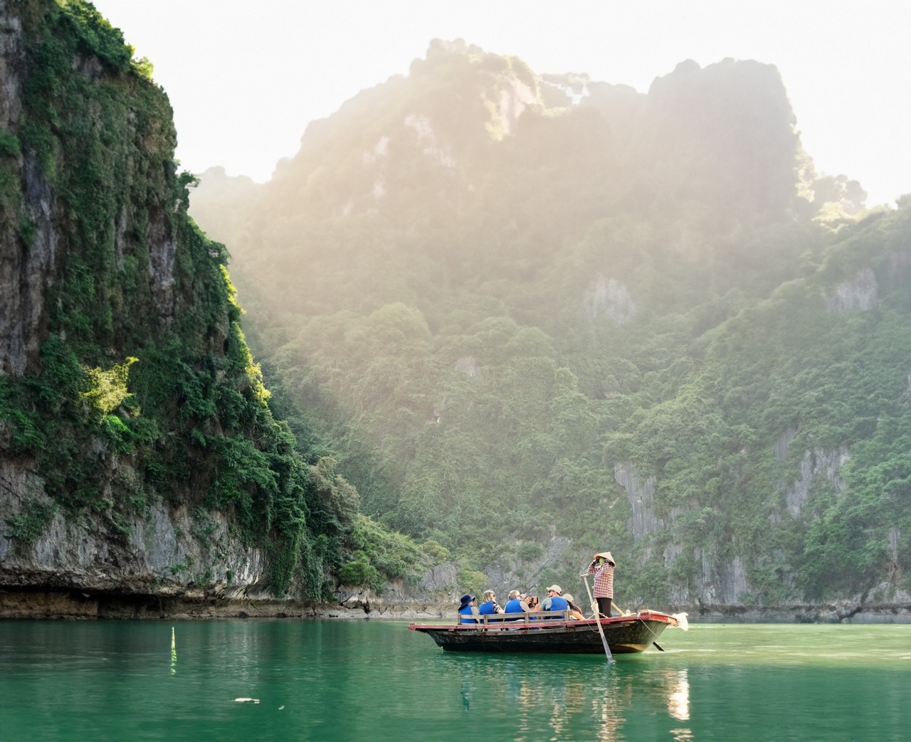 Tranquil boat tour through lush green limestone karsts in Halong Bay, Vietnam.