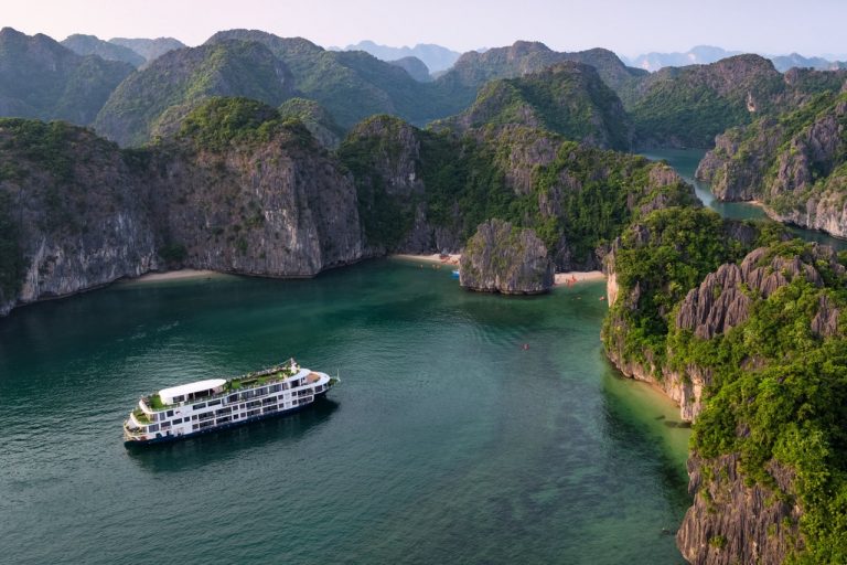 Stunning view of Halong Bay with a cruise sailing among limestone karsts and emerald waters.