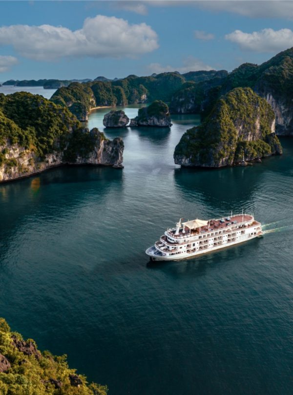 Stunning view of Halong Bay with a luxury cruise sailing among limestone karsts and emerald waters.