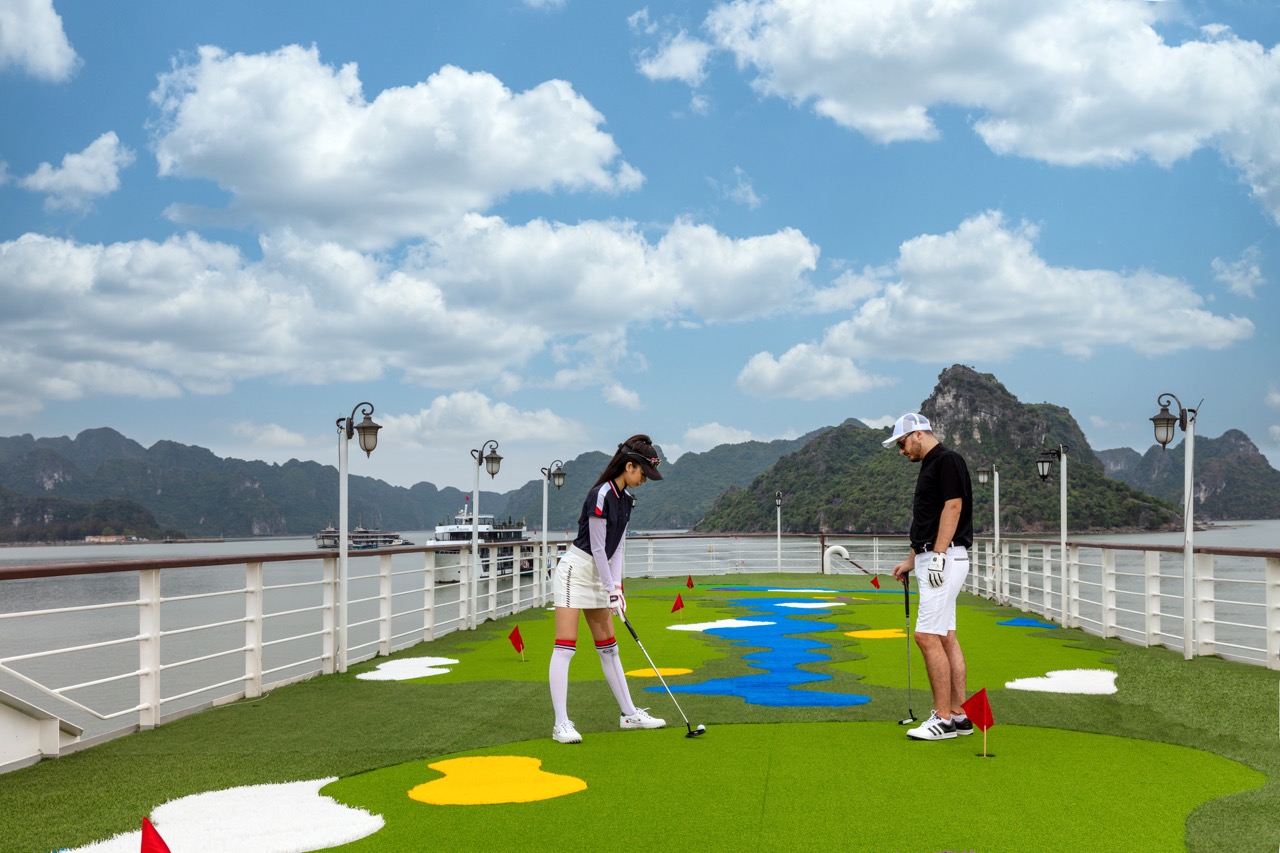 Enjoying a relaxing golf game on the deck of Mon Cheri Cruise with stunning Halong Bay scenery.