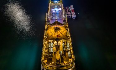 Night view of luxury cruise in Halong Bay with illuminated deck and calm waters, perfect for a sceni.