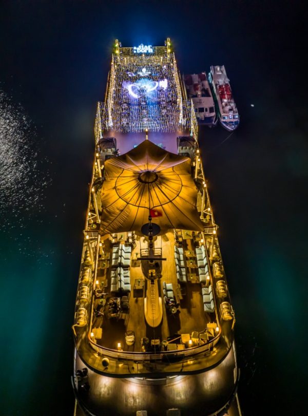 Night view of luxury cruise in Halong Bay with illuminated deck and calm waters, perfect for a sceni.