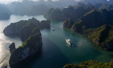 Drone view of Stellar Of The Seas weaving through dramatic karst islands in Lan Ha Bay, Vietnam. Let ViettrendTour craft your dream Halong Bay cruise itinerary.