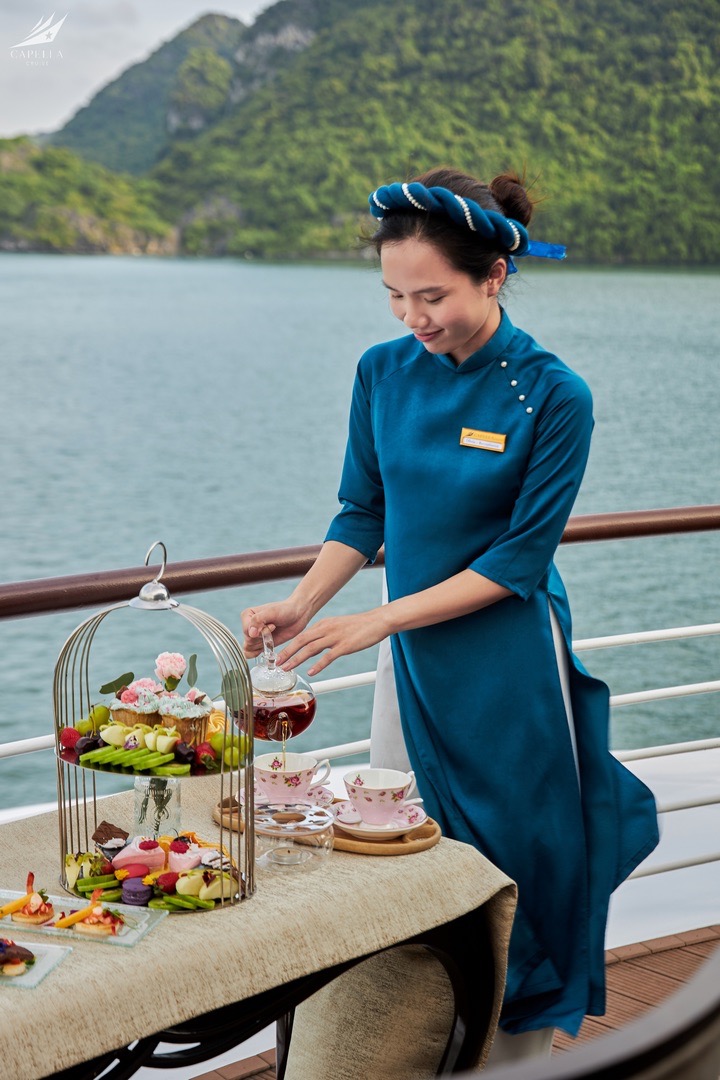 Elegant cruise staff preparing afternoon tea on a luxury voyage in scenic nature setting.