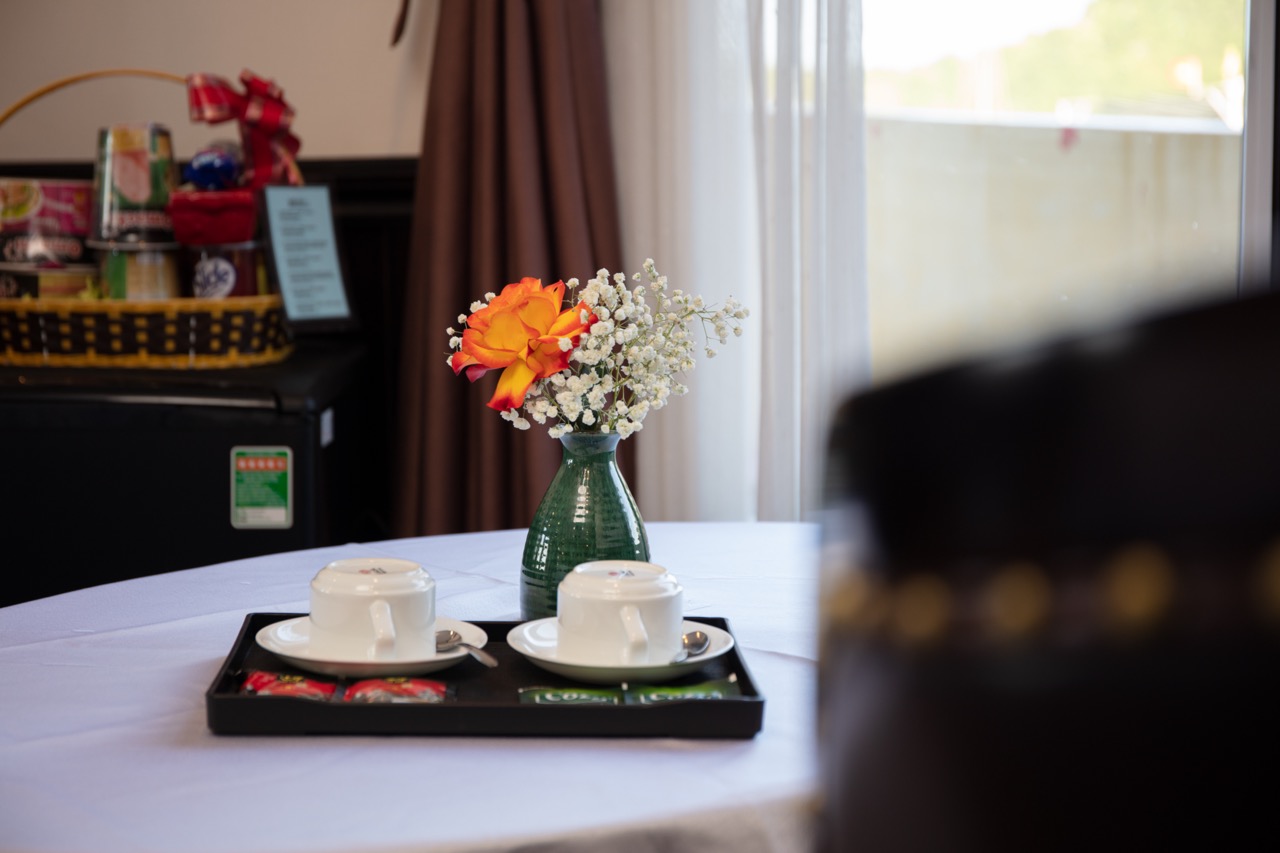 Cozy hotel room setup with tea cups, floral centerpiece, and natural sunlight for a relaxing stay.