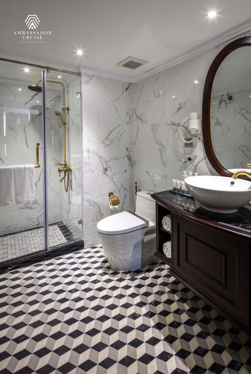 Luxurious bathroom on Halong Bay cruise showcasing elegant marble walls and modern fixtures.
