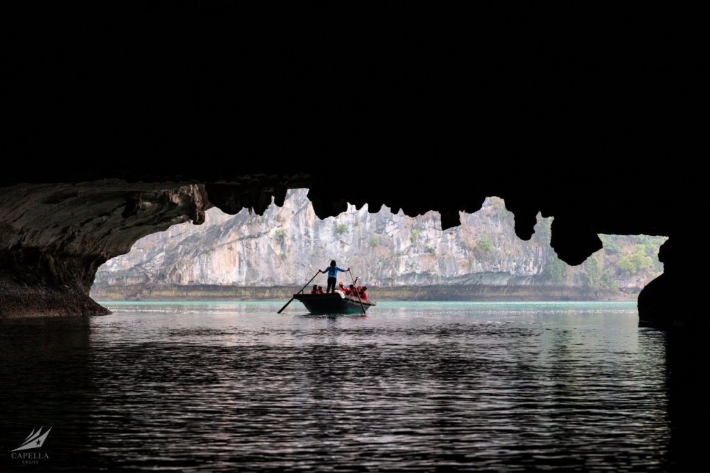 A boat cruising through a scenic water cave with stunning rock formations and lush cliffs.