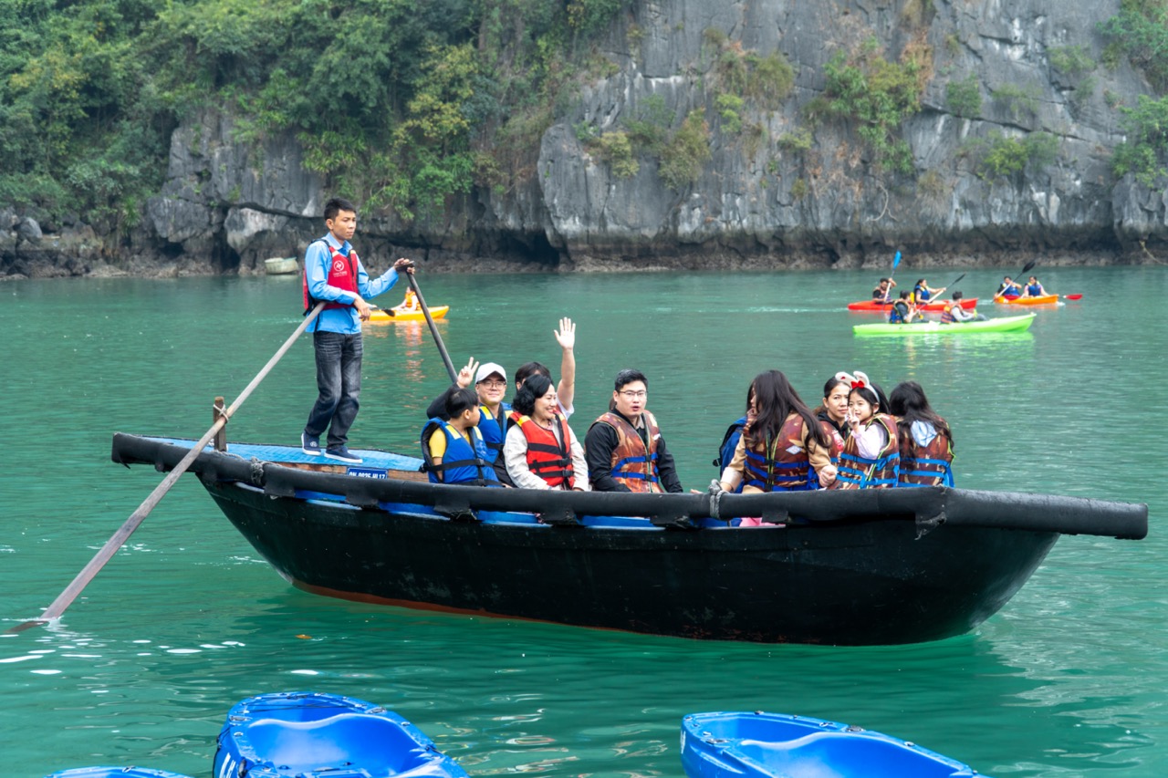 Enjoying group boat tour and kayaking adventure on stunning turquoise water in Vietnam.