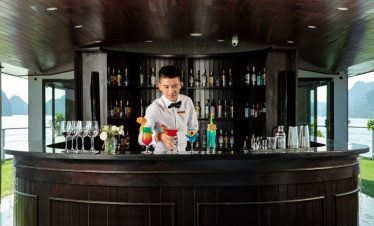 Elegant bartender preparing colorful cocktails on a luxury cruise in Halong Bay.
