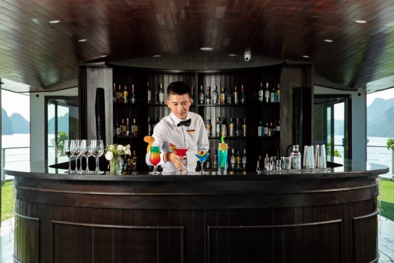 Elegant bartender preparing colorful cocktails on a luxury cruise in Halong Bay.