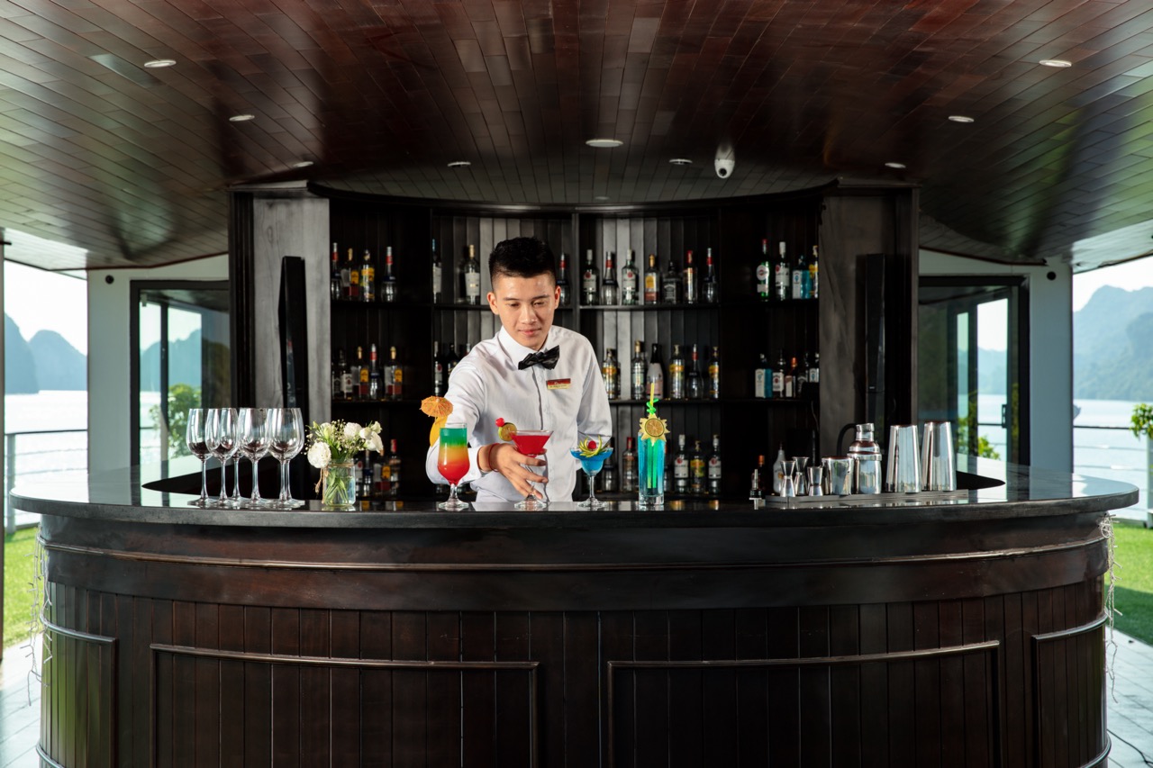 Elegant bartender preparing colorful cocktails on a luxury cruise in Halong Bay.