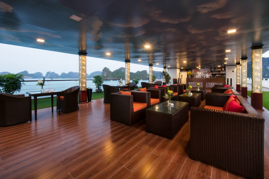 Spacious cruise lounge with panoramic views of Halong Bay, elegant seating, and relaxing ambiance.