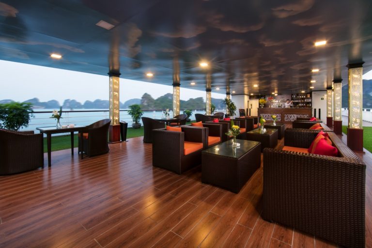 Spacious cruise lounge with panoramic views of Halong Bay, elegant seating, and relaxing ambiance.