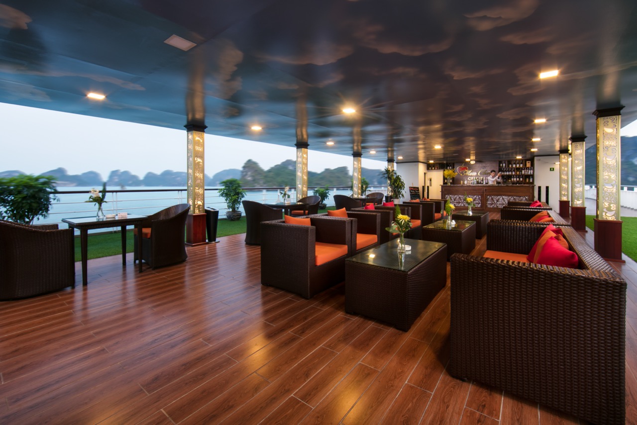 Spacious cruise lounge with panoramic views of Halong Bay, elegant seating, and relaxing ambiance.