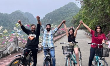 Cyclists enjoying a joyful ride along a mountain road in Lan Ha Bay, surrounded by lush greenery and.