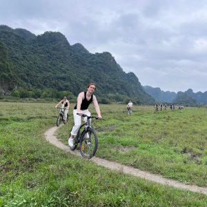 Cycling a grassy meadow trail near karst mountains.
