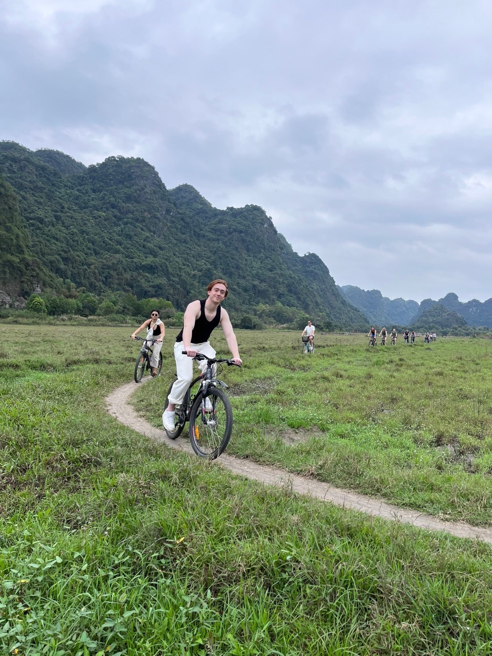 Mountain biking along lush trails in Lan Ha Bay with scenic mountain views and a joyful atmosphere.