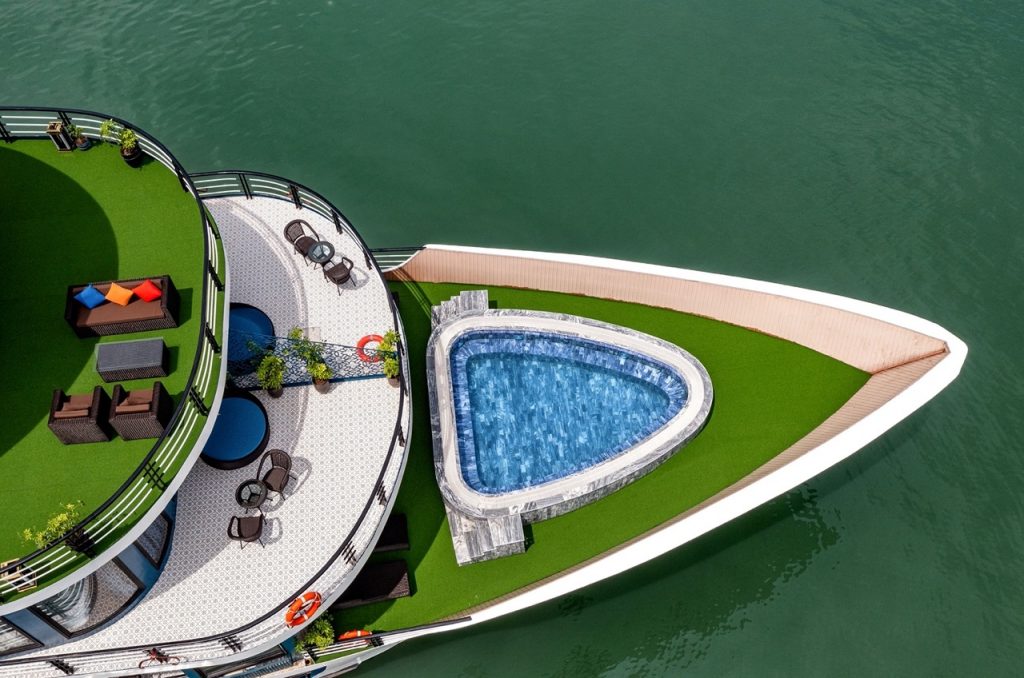Stunning aerial view of a luxury cruise in Halong Bay featuring an infinity pool and spacious deck,.