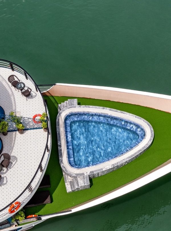 Stunning aerial view of a luxury cruise in Halong Bay featuring an infinity pool and spacious deck,.