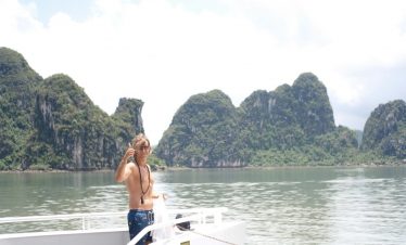 Stunning Lan Ha Bay scene with a woman enjoying a cruise balcony, lush limestone islands, and tranqu.