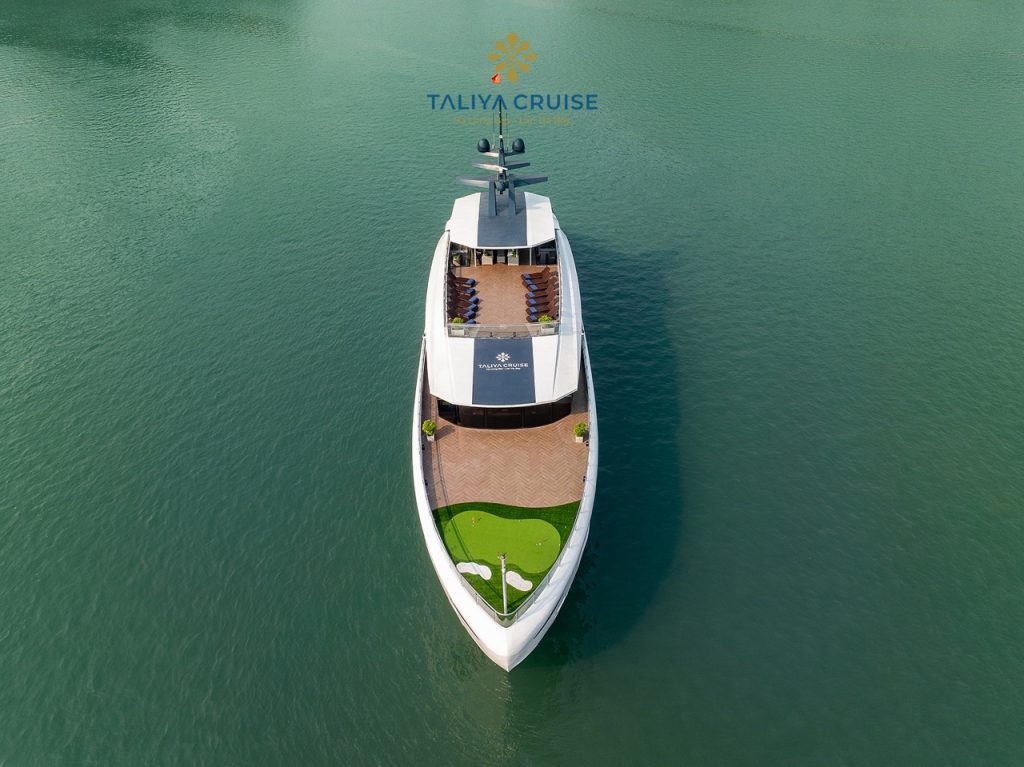 Aerial view of luxury cruise boat sailing on Halong Bay with calm waters and scenic limestone karsts.