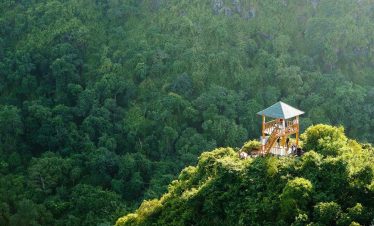 Breathtaking view of green forested mountain with a small pavilion, perfect for nature lovers and ad.
