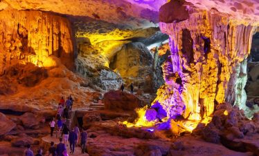 Vivid cave interior with colorful lighting and visitors exploring the stunning formations.