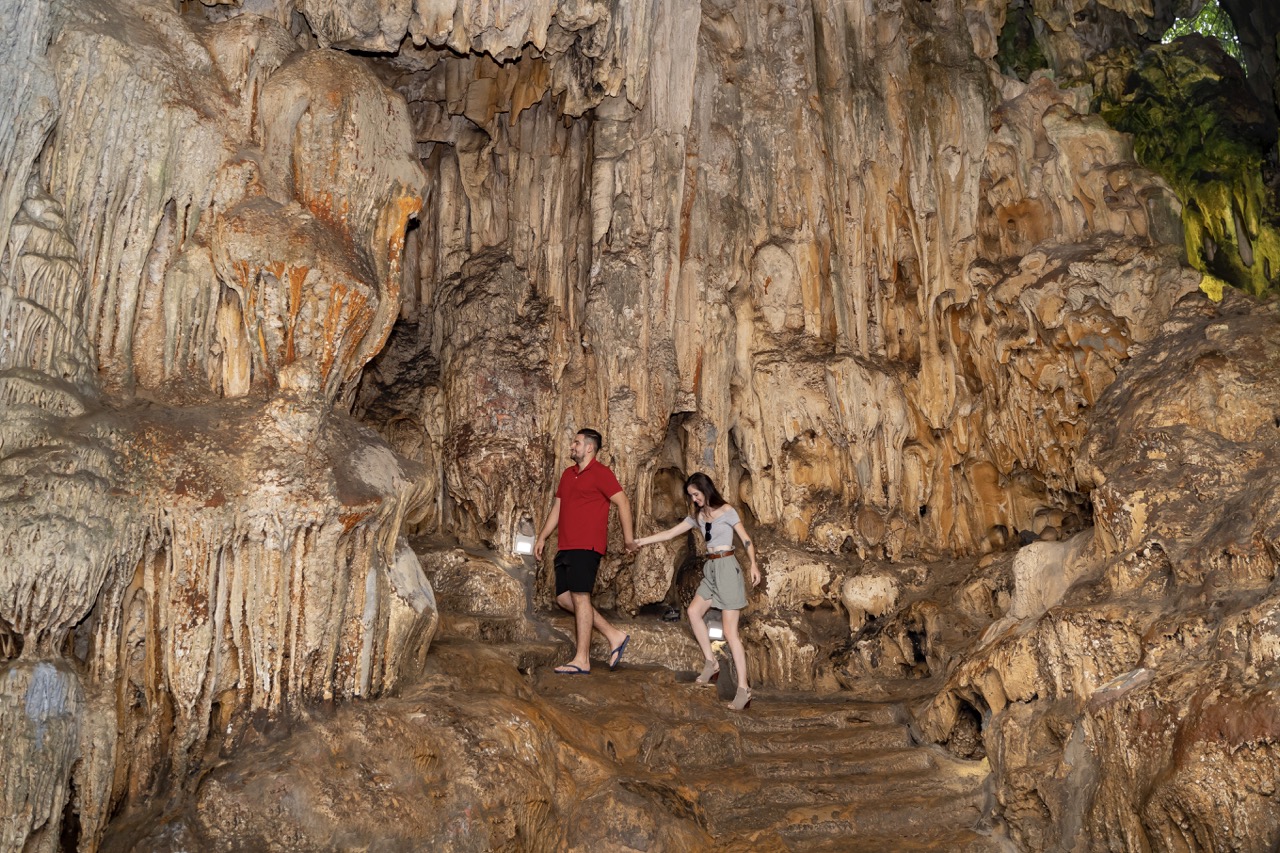 Stunning cave exploration with couple amid stalactites and stalagmites in Vietnam.