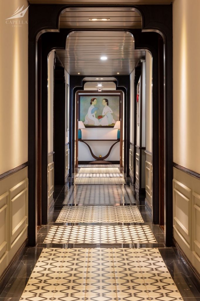 Elegant cruise hallway with intricate tile flooring and artistic wall decor.
