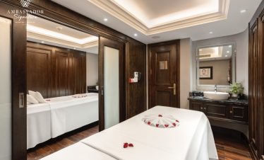 Luxurious cruise cabin with elegant wooden decor, cozy bed, and modern amenities on Halong Bay.