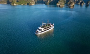 Aerial view of a luxury cruise boat sailing through the stunning limestone karsts of Halong Bay, per.