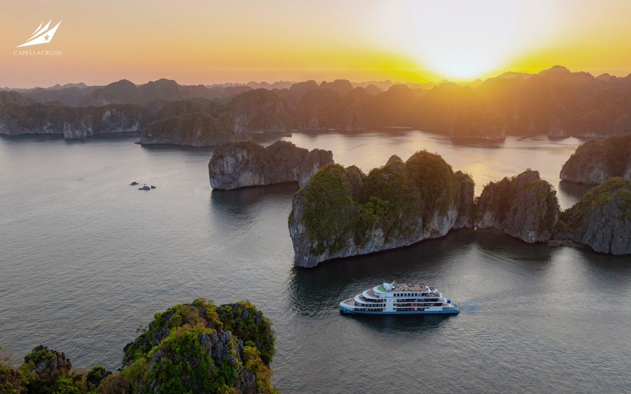 Halong Bay Tours - Boat cruising through scenic limestone karsts at sunset in Ha Long Bay, Vietnam.