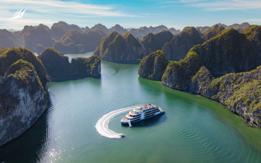 Spectacular boat cruising through emerald waters amidst towering limestone islands in Ha Long Bay, Vietnam.
