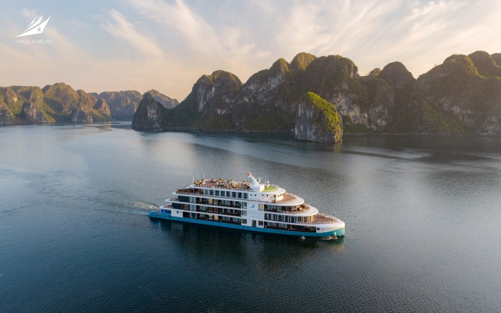 Luxury cruise boat sailing through stunning limestone karsts on Halong Bay, Vietnam.