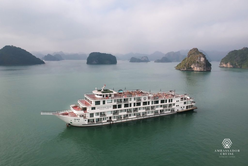 Cruise ship sailing through Halong Bay with limestone karsts and calm waters.