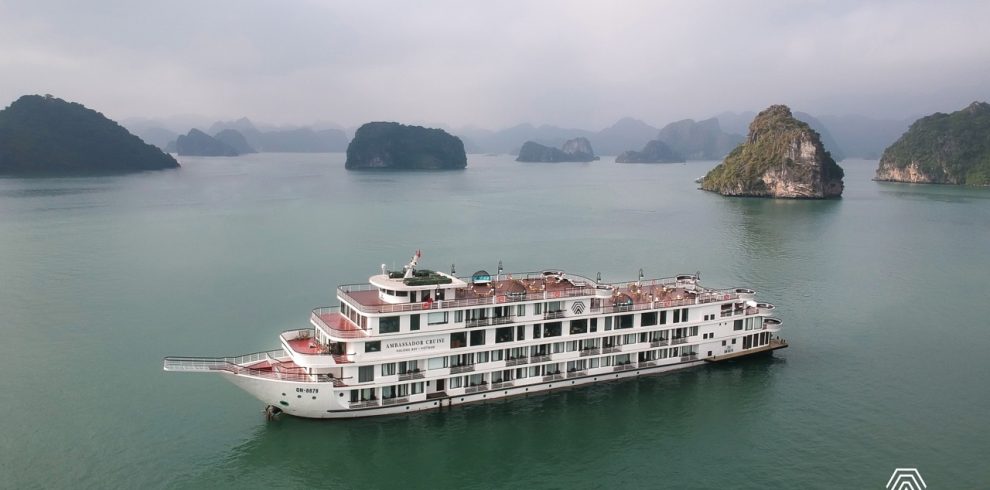 Cruise ship sailing through Halong Bay with limestone karsts and calm waters.