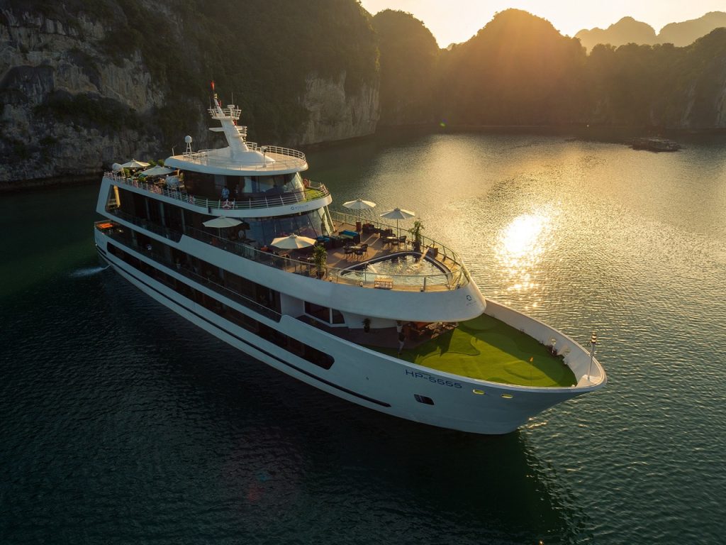 Luxurious cruise boat sailing in stunning Halong Bay at sunset, Vietnam.