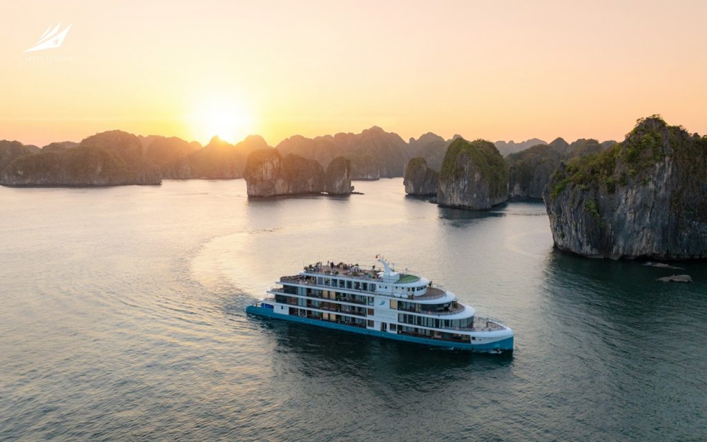 Luxurious boat cruising in Ha Long Bay during sunset with limestone islands - Capella Cruise Halong Bay