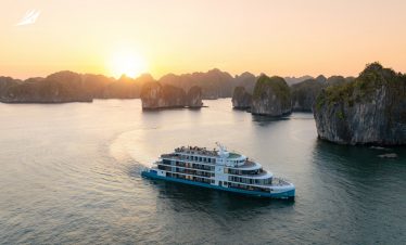Luxurious boat cruising in Ha Long Bay during sunset with limestone islands - Capella Cruise Halong Bay