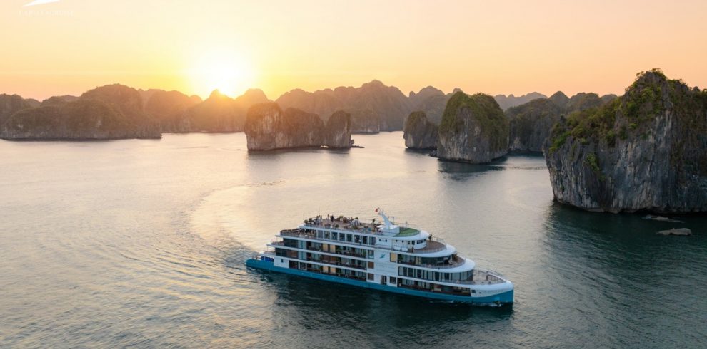Luxurious boat cruising in Ha Long Bay during sunset with limestone islands - Capella Cruise Halong Bay