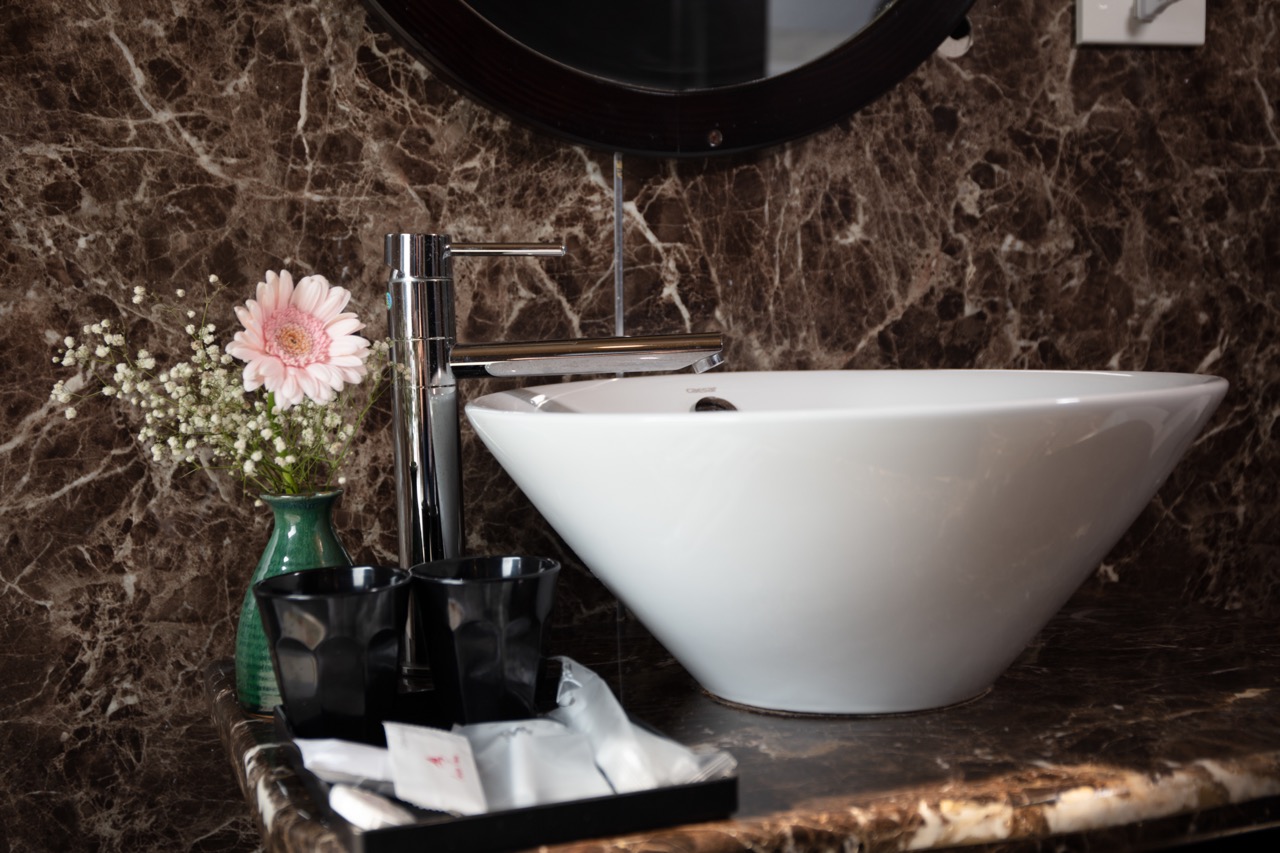 Elegant modern bathroom sink with marble countertop and decorative flower arrangement for a luxurious travel experience.